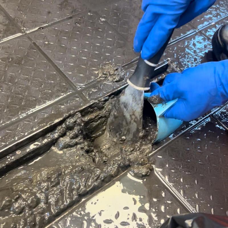 Trench drain clogged with mud being cleaned