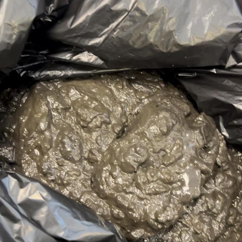 Trench drain mud buildup removed in black trash bag