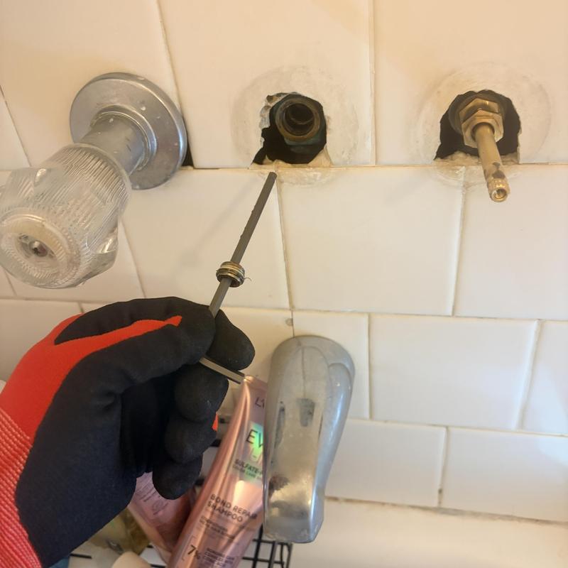 Three-handle shower valve cartridge replacement in progress