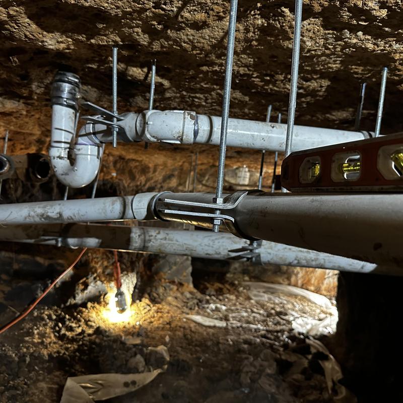 Schedule 40 PVC drain lines suspended in crawl space