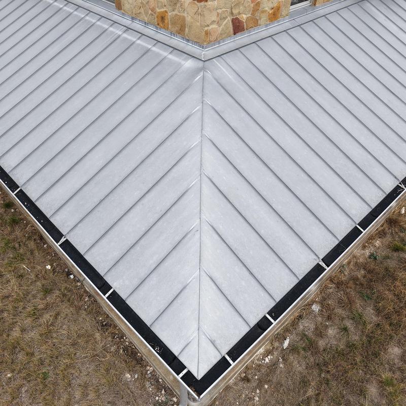 Standing seam metal roof corner with stone chimney