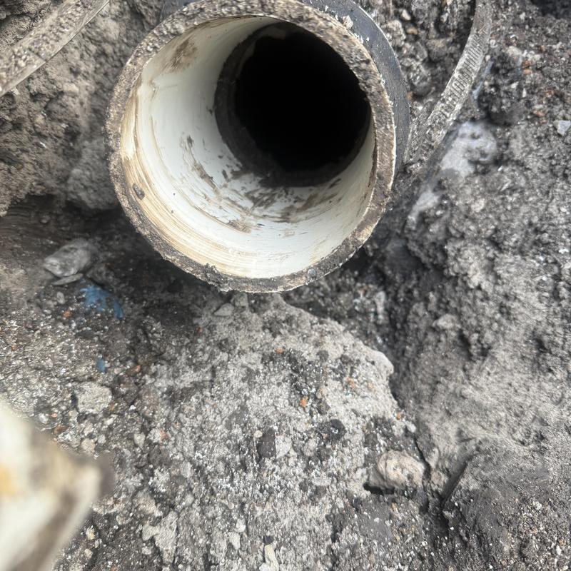 Sewer line installation with exposed pipe end in soil Sewer line installation with exposed pipe end in soil