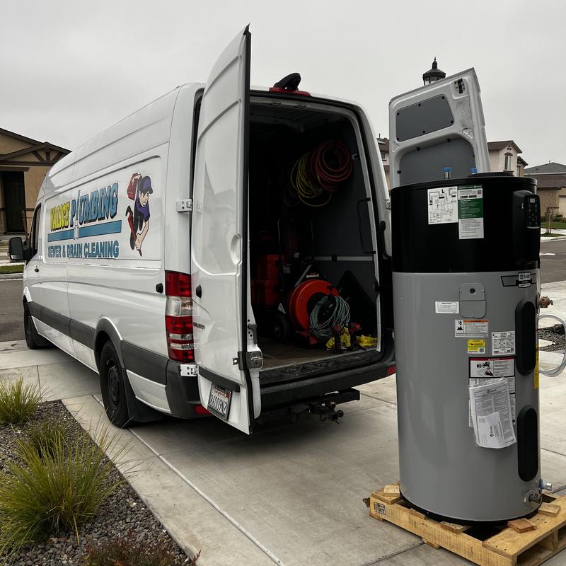 Water heater on pallet by open plumbing van