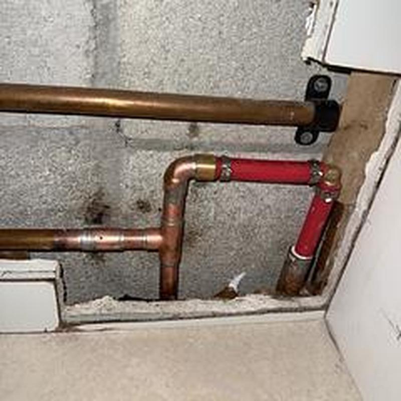 Copper and PEX plumbing pipes inside drywall access panel