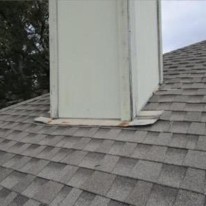Chimney base flashing with rusted sections on shingles