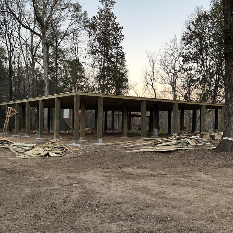 Foundation piers elevated on wooden beams in forest setting Foundation piers elevated on wooden beams in forest setting