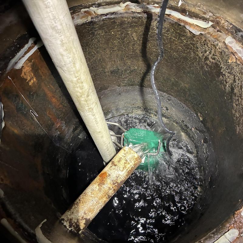 Sump pump basin with new green pump installed