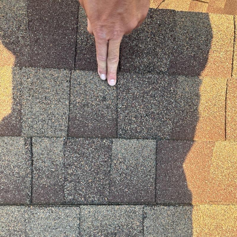 Asphalt roof shingles inspection with hand pointing