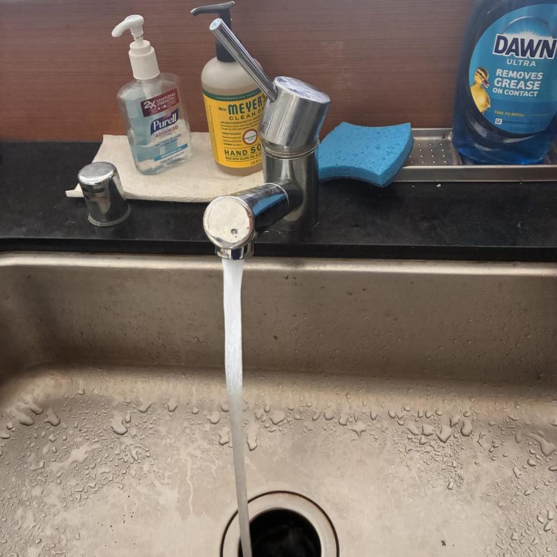 Kitchen faucet with running water and cleaning supplies