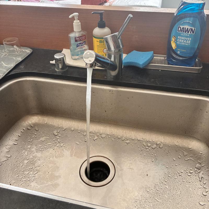 Kitchen faucet with running water and cleaning supplies