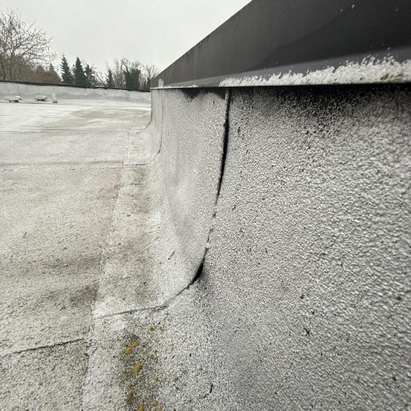 Flat roof membrane with seam damage near flashing
