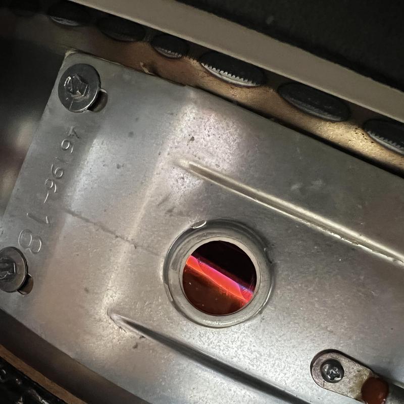 Water heater burner flame visible through inspection port