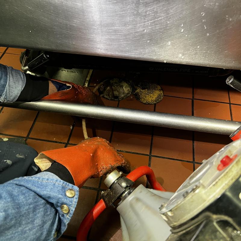 Floor drain snake cleaning under commercial sink