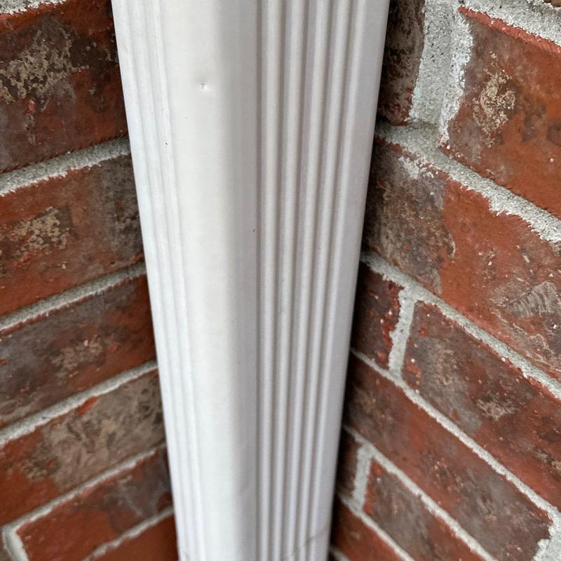 Downspout dent on brick exterior wall close-up