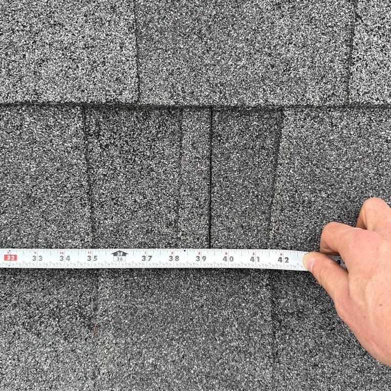 Asphalt shingle roofing with measuring tape on hail damage