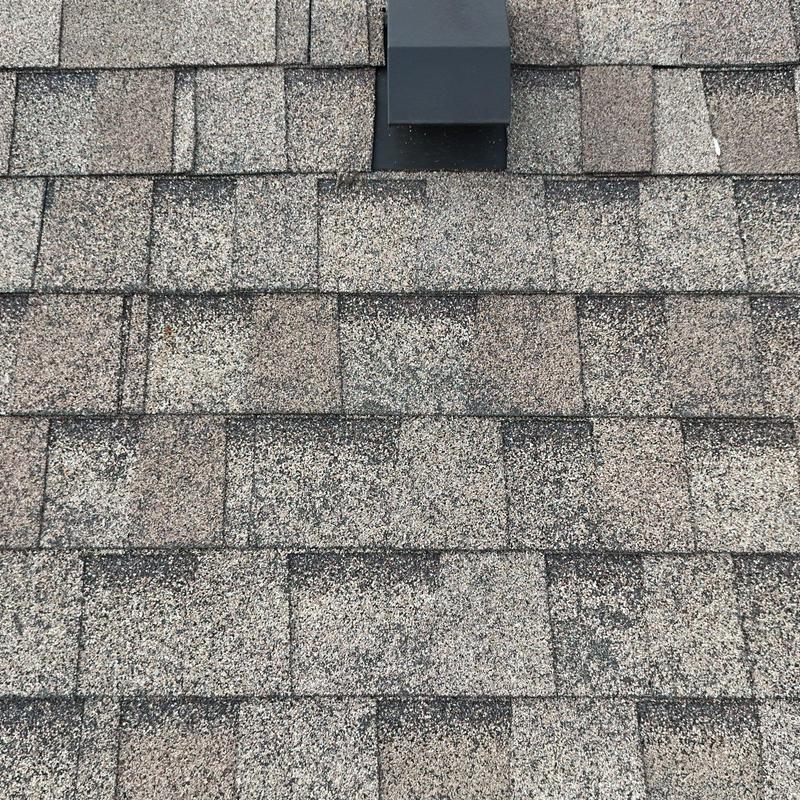 Asphalt shingle roof with hail damage near roof vent