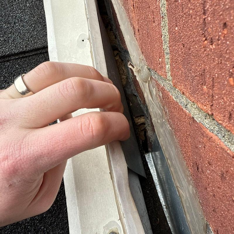 Roof flashing inspection near brick wall gap