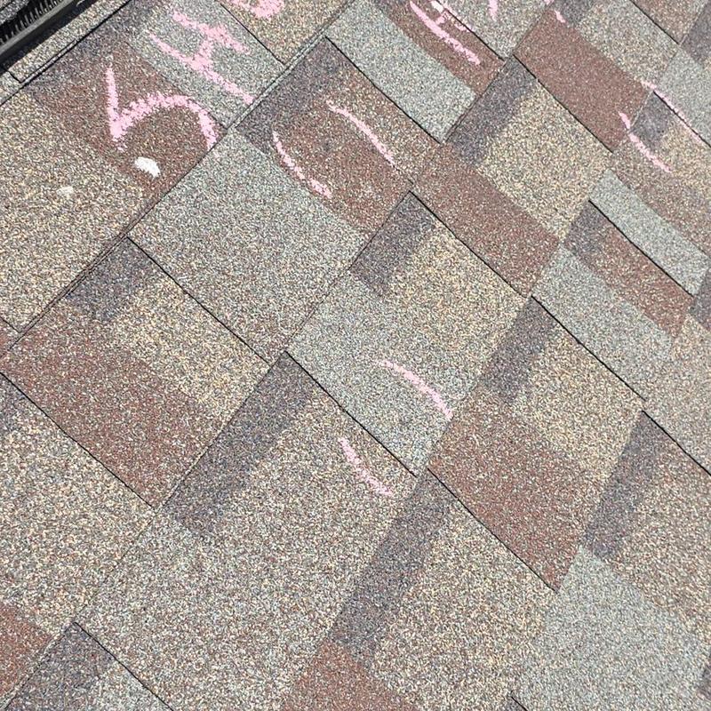 Asphalt roof shingles with hail impact marks