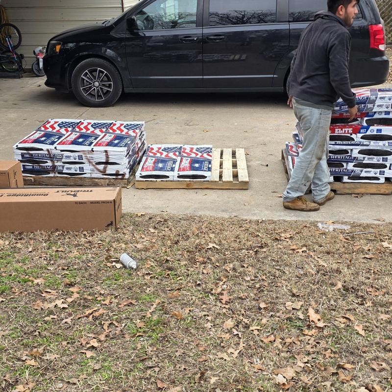 Roofing shingles stacked on pallets near van