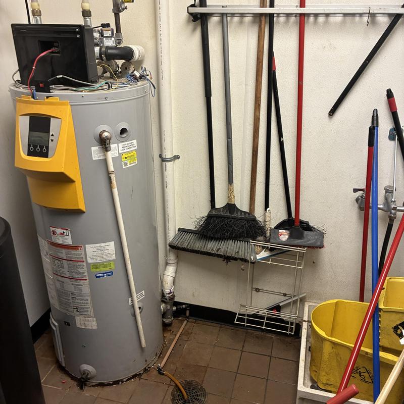 Commercial water heater with open control panel and tools nearby