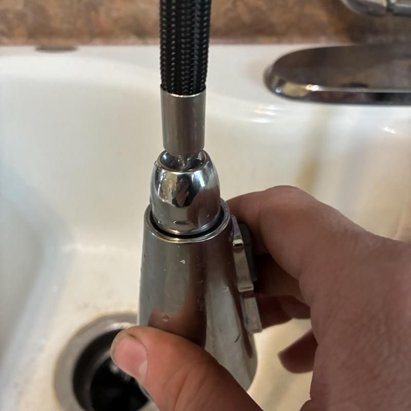 Kitchen faucet sprayer head being tightened by hand