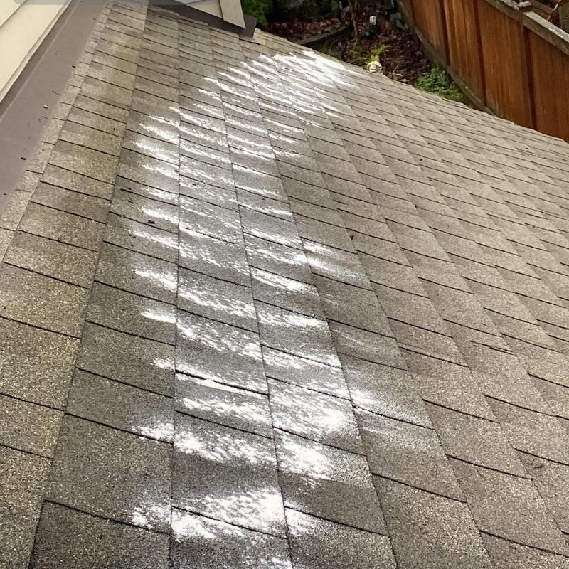 Asphalt shingle roof with sunlight reflections