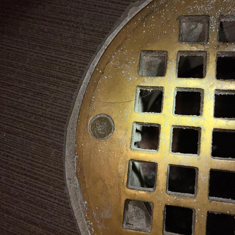 Brass shower drain cover drilled for clog removal