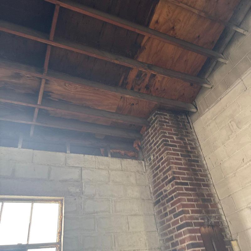 Roof sheathing and framing exposed above brick chimney