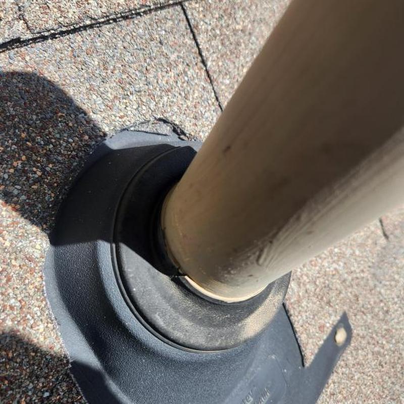 Roof pipe flashing on shingle roof in sunlight