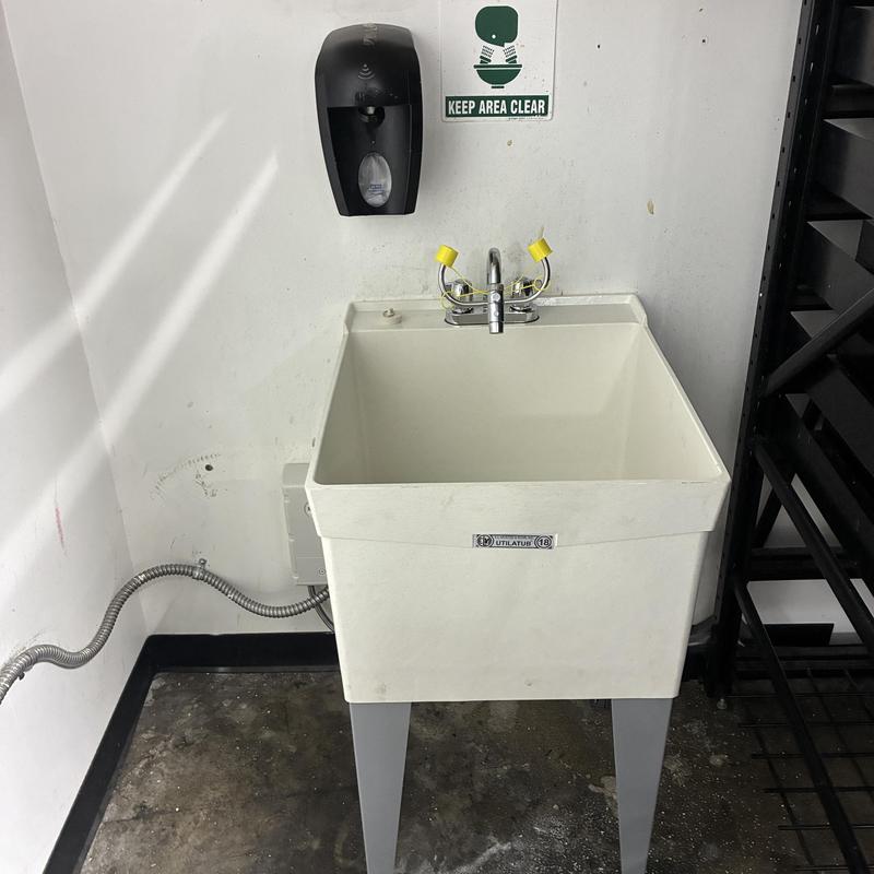 Utility tub with faucet and eyewash station in corner