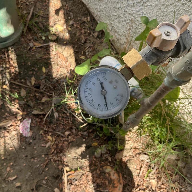 Water pressure gauge on outdoor pipe valve in garden