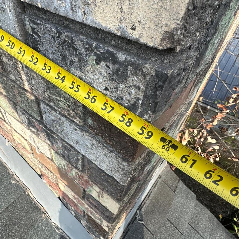 Chimney brickwork with measuring tape at roof edge