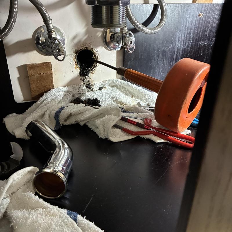 Vanity sink drainpipe with plumbing tools under cabinet