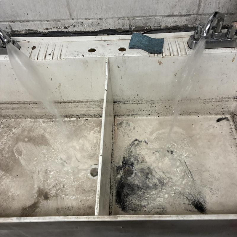 Utility sink with running water in workshop restroom