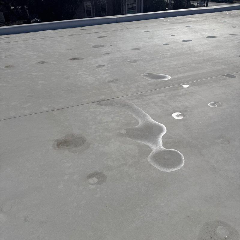 Flat commercial roof with hail damage and water pooling