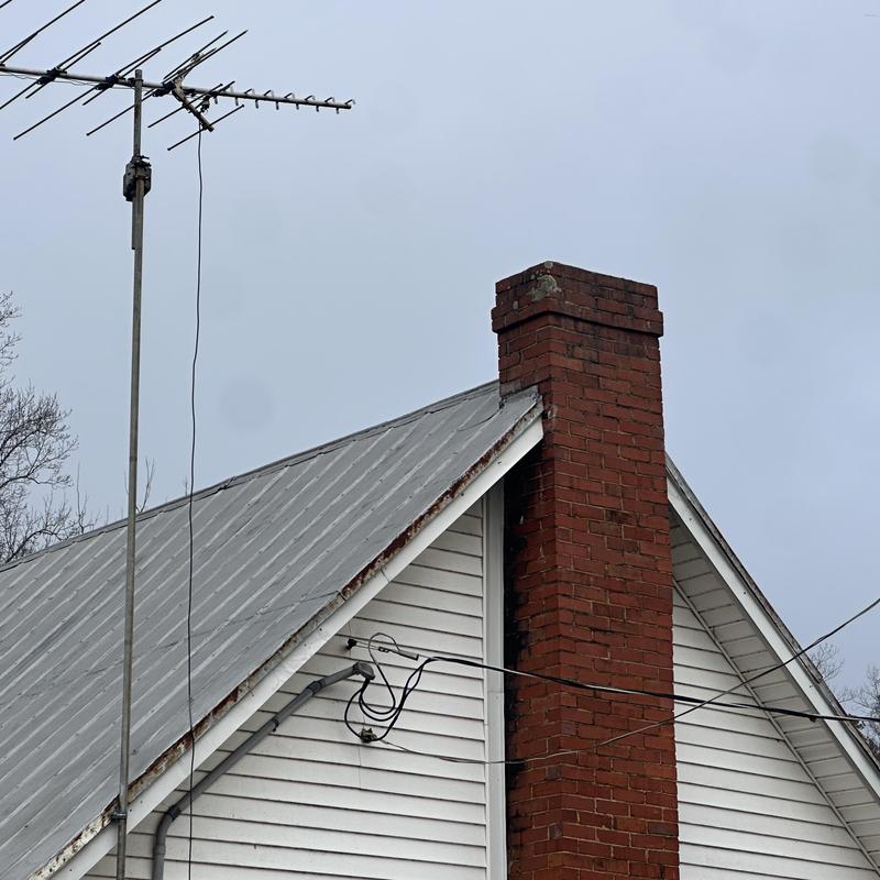Metal roof with brick chimney and TV antenna installation