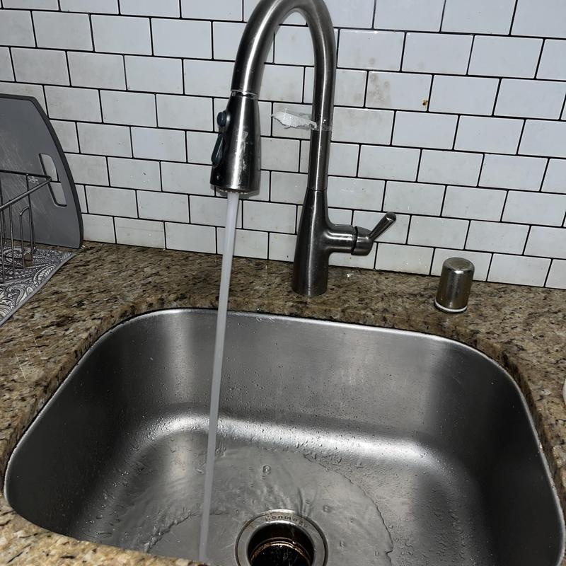 Kitchen faucet with running water over stainless steel sink
