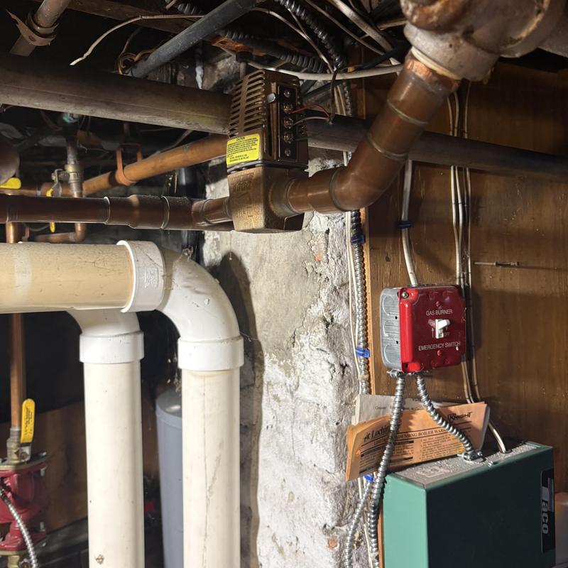 Zone controller head on copper heating pipes in basement