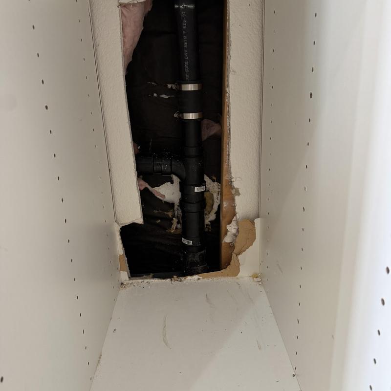 Kitchen drain pipe with wall access hole in cabinet