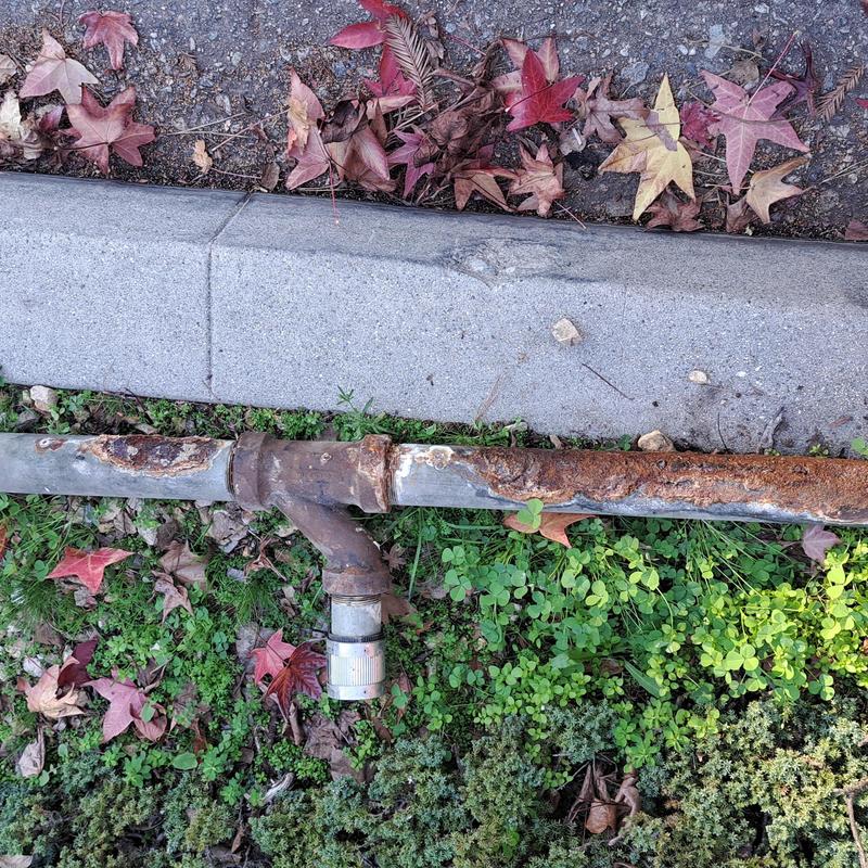 Cast iron drain pipe rusted and corroded near curb Cast iron drain pipe rusted and corroded near curb