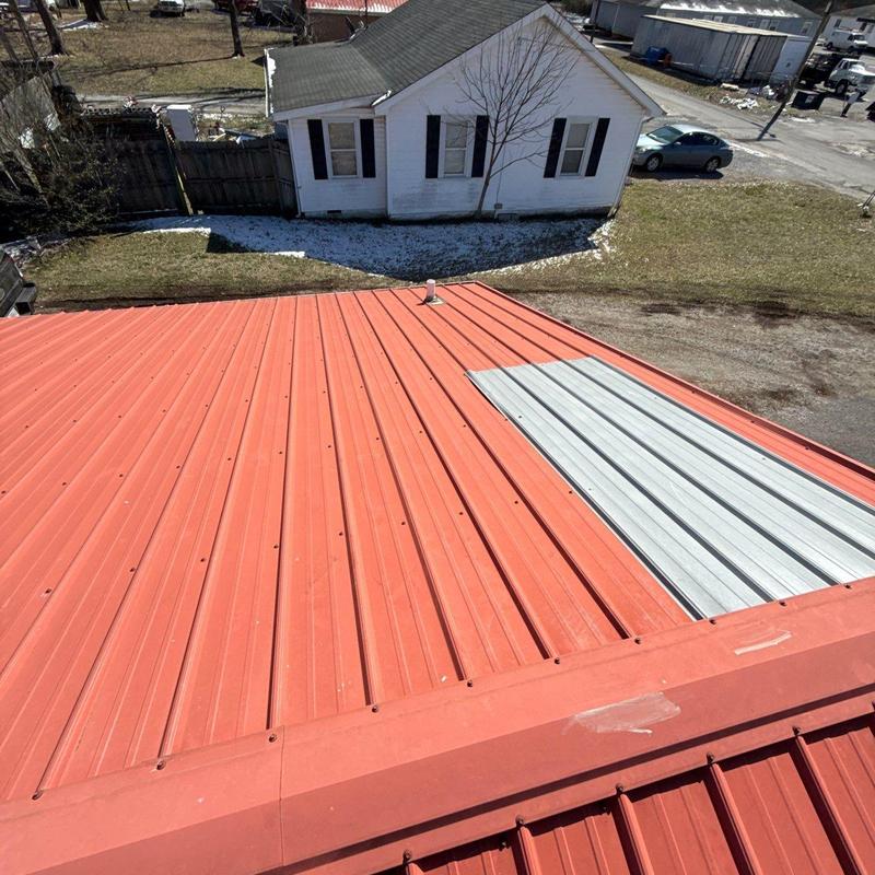 Metal roof panel with replacement section installed