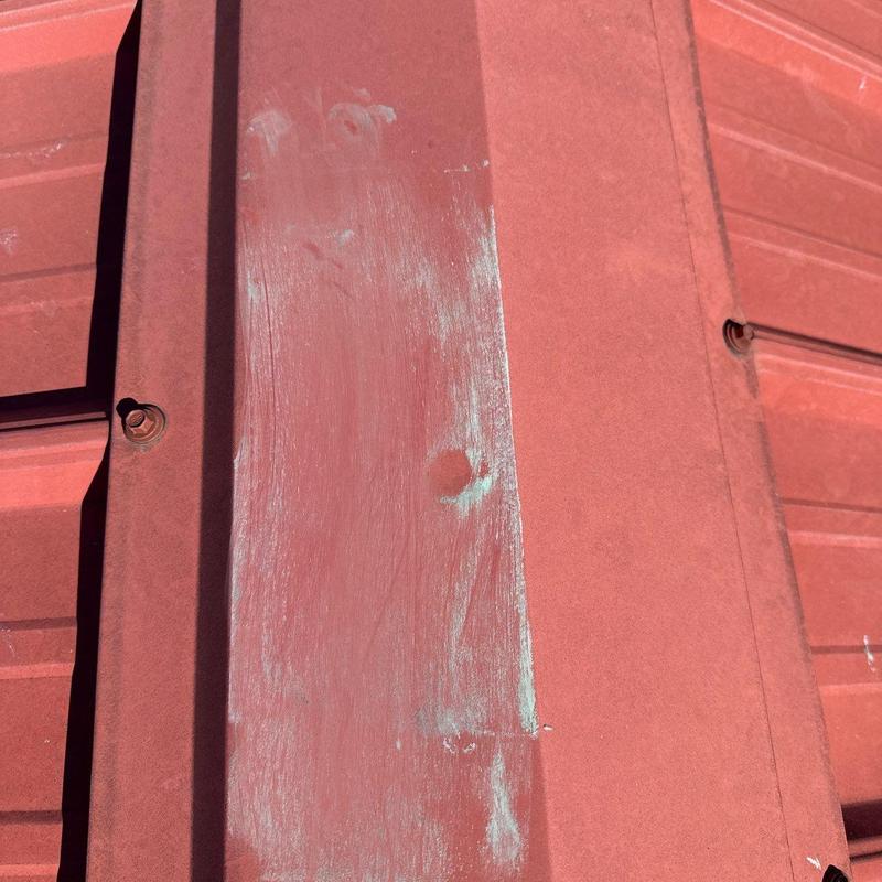 Metal roof panel with hail damage and paint wear
