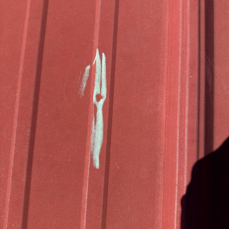 Metal roof panel with hail damage and markings