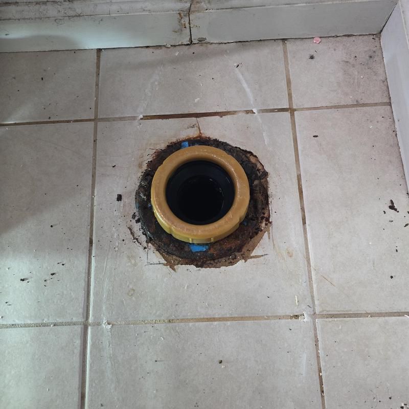 Toilet closet flange on tiled floor with rust damage