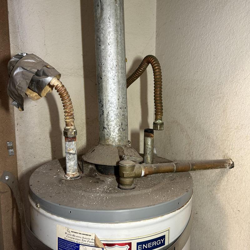 Old water heater with corroded vent and pipes