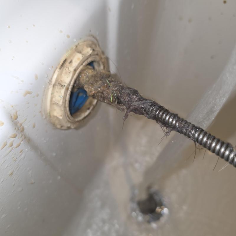 Bathroom tub drain clogged with hair on sewer machine cable