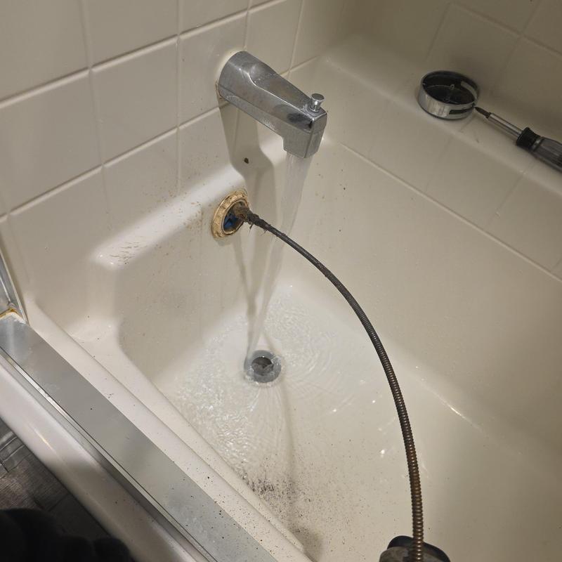 Bathroom tub drain with sewer machine cable clearing clog