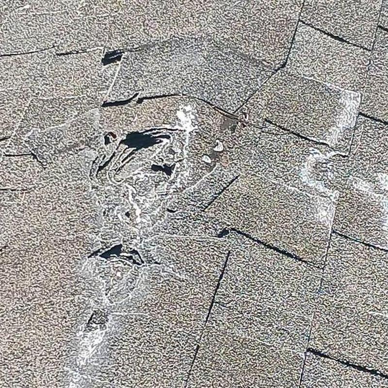 Damaged asphalt roof shingles with visible wear and tear