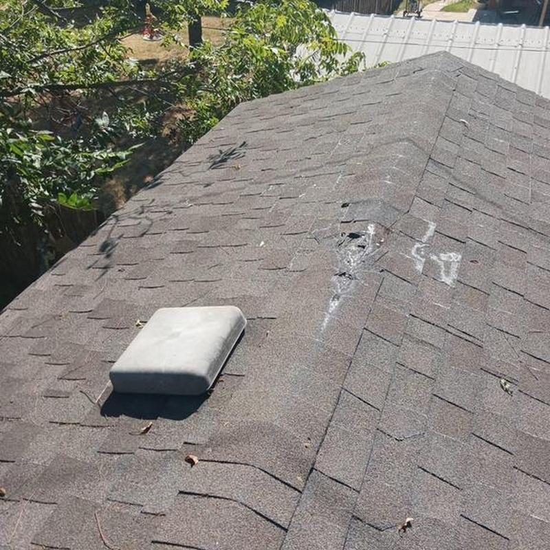Asphalt shingle roof with damaged area marked for inspection