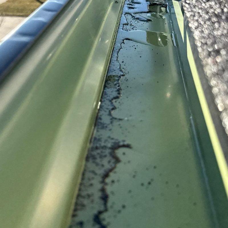 Aluminum gutter with debris and water buildup close-up